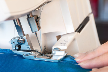 Women's hands at work on sewing machine. Overlock sewing.