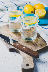 Water with lemon in the glass and fresh lemons on bright background. Diet or weight loss concept