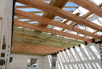 Obraz premium The wooden structure of the building. Wooden frame building. Wooden roof construction. photo for home. house building. Installation of wooden beams at construction the roof truss system of the house.