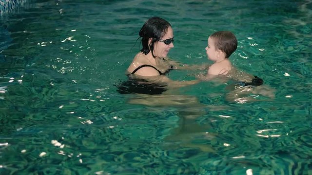 Happy mother teaching to son in swimming pool 4k