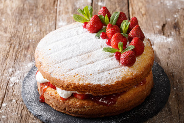 Home Victoria sponge cake, decorated with strawberries and mint closeup. Horizontal