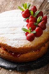 Victoria sandwich cake decorated with strawberries and mint closeup. vertical