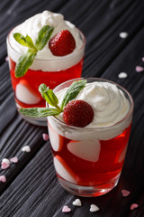 Delicious strawberry dessert with whipped cream, decorated with hearts close up in a glass. vertical