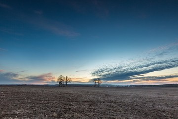Beautiful colorful sunset sky over plowed field in springtime