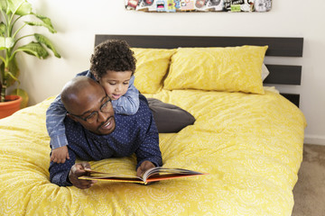 Father reading book to son on bed
