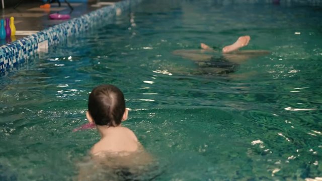 Happy mother teaching to son in swimming pool 4k