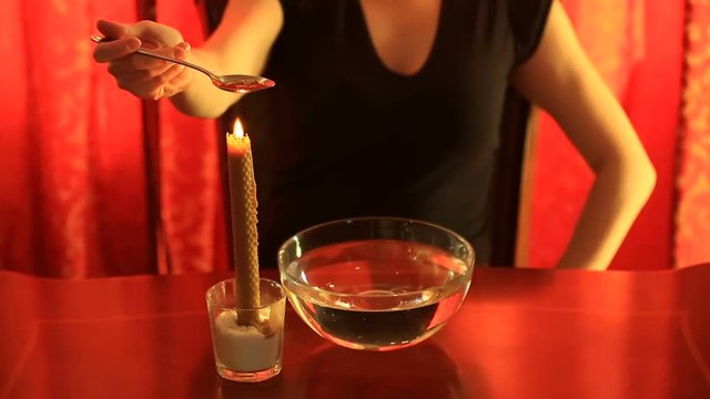 Divination with candle. woman pouring wax into the water