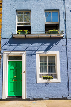 Light blue restored Victorian British house facade exterior with green door and white windows
