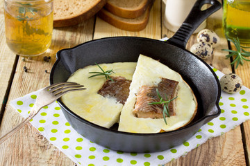 Omelette with red fish in a cast-iron frying pan on a wooden table. The concept of a healthy diet and diet.