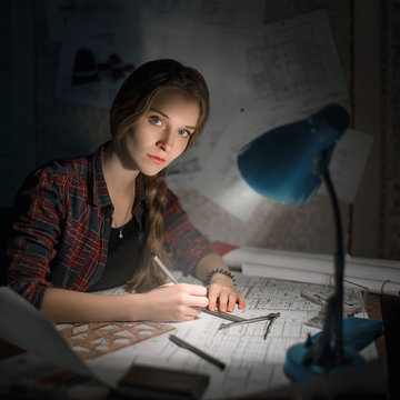 Caucasian woman drawing on blueprint at night