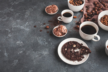 Chocolate cake, cups of coffee, chocolate muesli and chocolate ice cream on dark background