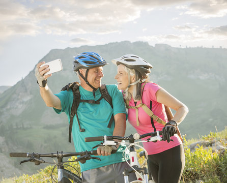 Caucasian couple with mountain bikes posing for cell phone selfie