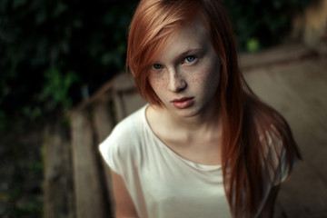 Closeup portrait of a young red-haired girl with freckles and blue eyes looking into the camera up