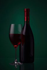 Bottle of red wine and glass on green