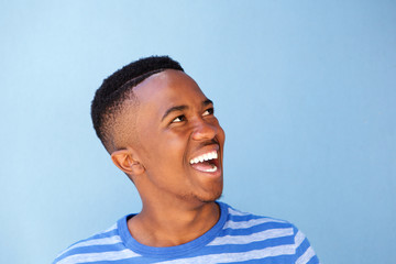 Close up young african man laughing against blue wall