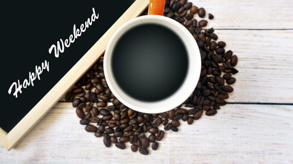 Heat a cup of coffee, coffee beans and a whiteboard with the word HAPPY WEEKEND