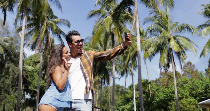 Couple Walk Outdoors Take Selfie Photo On Cell Smart Phone Under Palm Trees, Happy Smiling Man And Woman Embrace Slow Motion 60