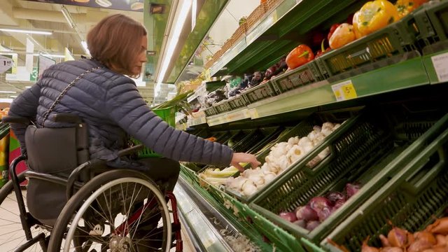 Disabled woman in a wheelchair choosing fruits and vegetables