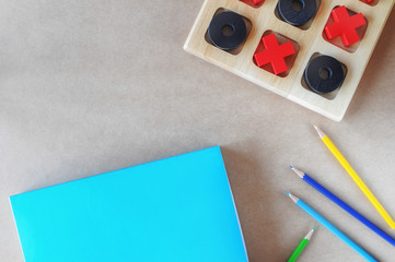 Flat lay of blank blue book with colored pencil, fern plant and wooden OX game on brown background,...