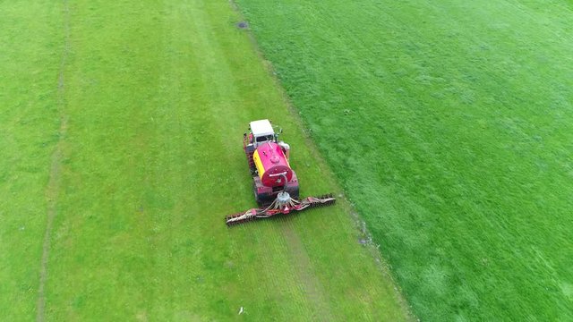Aerial view following modern agricultural machinery tractor manure injector which injects manure under soil instead of spreading it over grassland machine is injecting the manure on pasture meadow 4k