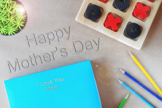 Happy mothers day and I love you mom words with blue book, colored pencil and wooden OX game, holiday and event concept