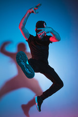The silhouette of one hip hop male break dancer dancing on colorful background