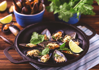 Baked shellfish mussels with cheese, cilantro and lime