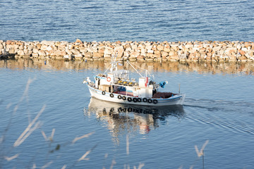 Obraz premium Small traditional wooden motor boat floating the calm waters in the harbour.Greece