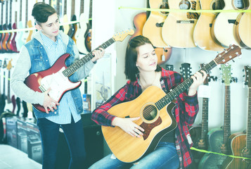 Obraz premium Teenagers examining both electric and acoustic guitars