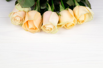 Bouquet of beige roses on white wooden vintage background, top view, copy space. Mothers day. Valentines day