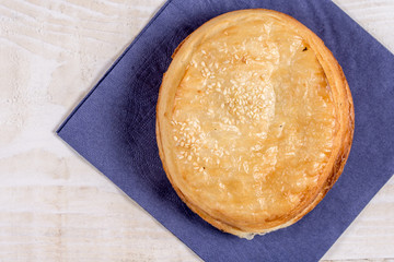 Round puff pastry with sesame on the napkin over wooden background