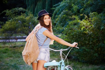 Pretty girl with bicycle in park