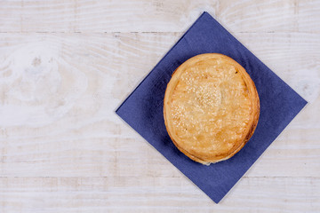 Round puff pastry with sesame on the napkin over wooden background