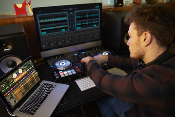 Young Man Composing Music on Laptop Computer in Bedroom
