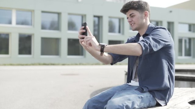 Junger Mann macht Selfies mit Smartphone mit Grimassen