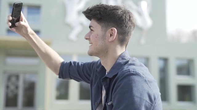 Junger Mann lacht in Smartphone Kamera