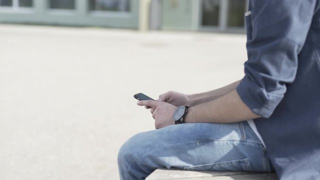 Junger Mann wischt am Smartphone und schaut sich Bilder an