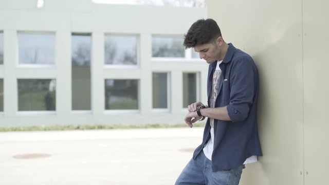 junger Mann schaut auf die Uhr und wartet