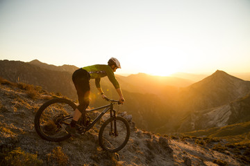 Cyclist man riding mountain bike at sunset