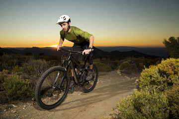 Cyclist man riding mountain bike at sunset