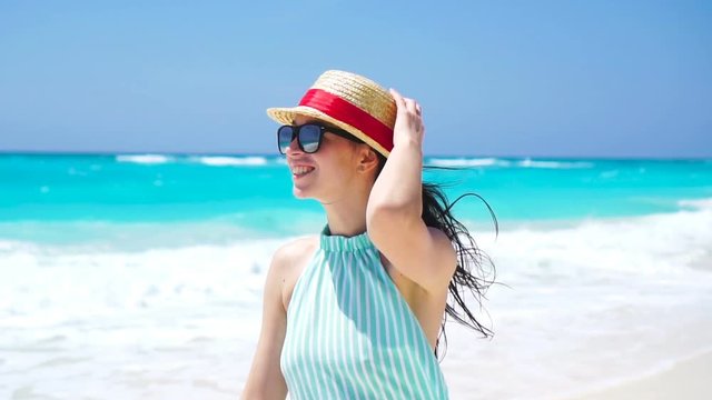 Beautiful woman on summer holidays smiling happy on white beach. Happy girl walking in summer dress. SLOW MOTION