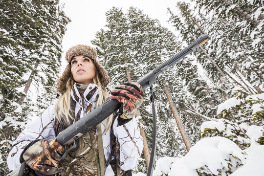Caucasian woman hunting in forest holding rifle