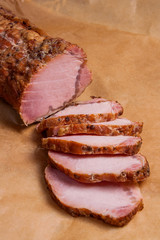 Close up view of sliced smoked meat or ham on brown packing paper..