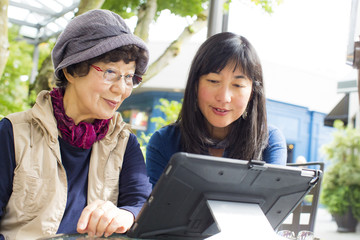 Older Japanese mother and daughter using digital tablet