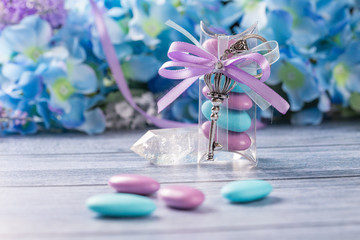 Wedding favors. Boxes with purple and white ribbon containing violet and blue confetti and key gift.
