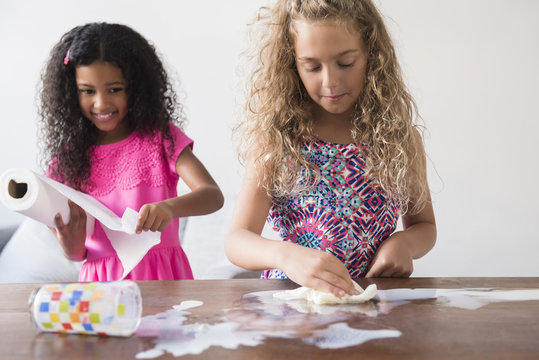 Girls Cleaning Spilled Milk On Table