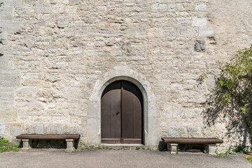 Alte Burgmauer mit Holztüre und zwei Holzbänken