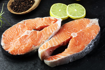 Fresh raw salmon fish steaks with fresh herbs on stone background