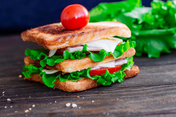 Breakfast sandwich and orange juice, tomatoes on the wooden table top view