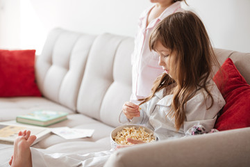 Obraz na płótnie Canvas Cute girl eating popcorn at home